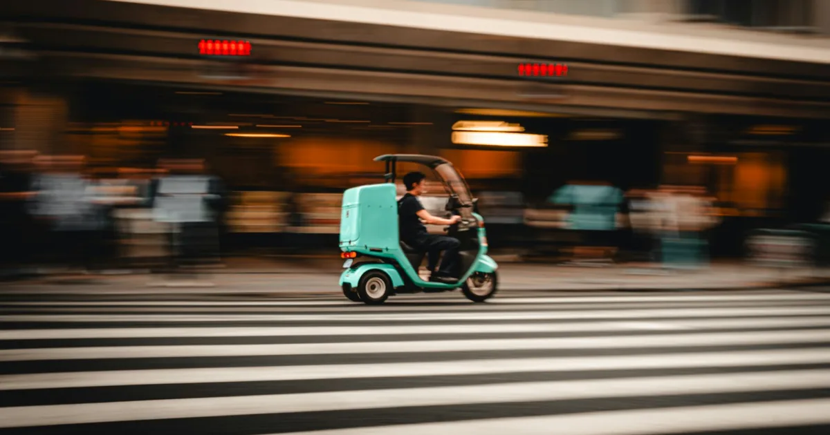 A food-delivery scooter crossing a street in Kyoto