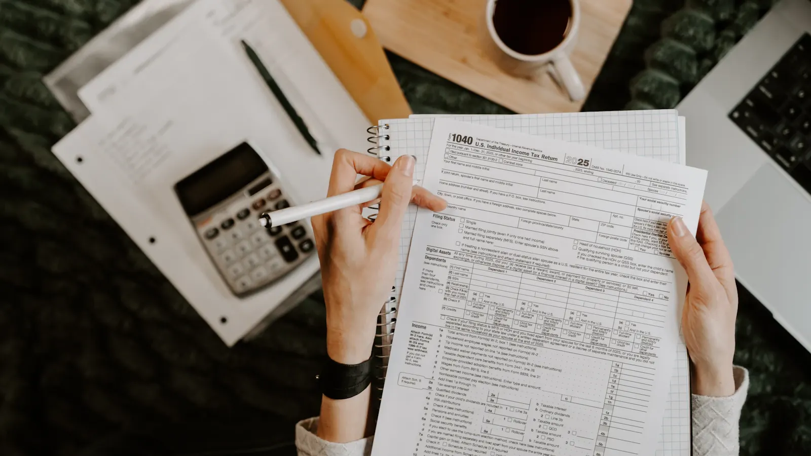 A person reviewing tax forms with a calculator and a cup of coffee