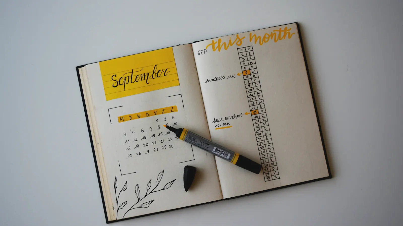 An open monthly planner with a pen resting on the page