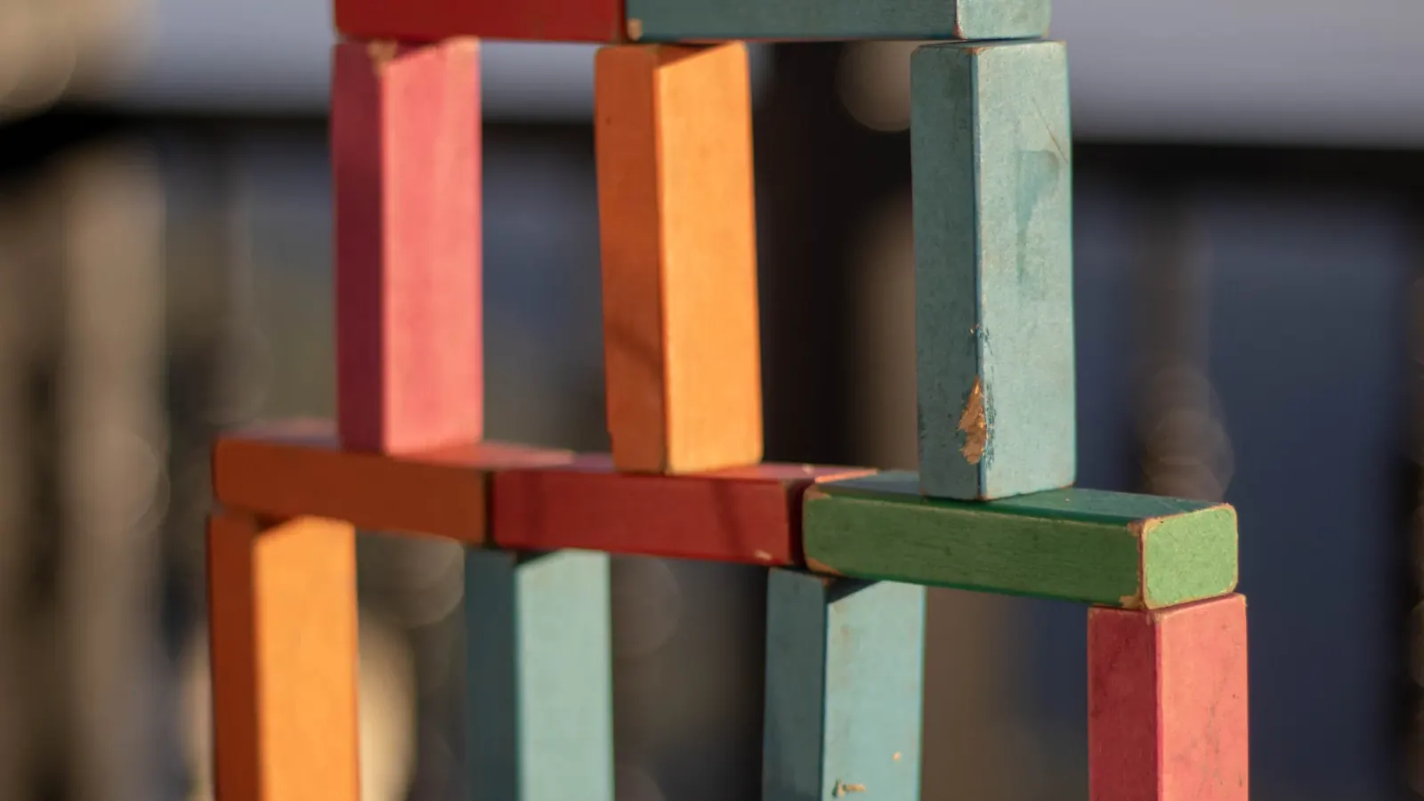 Colorful wooden blocks stacked into a small tower, each layer resting on the one below