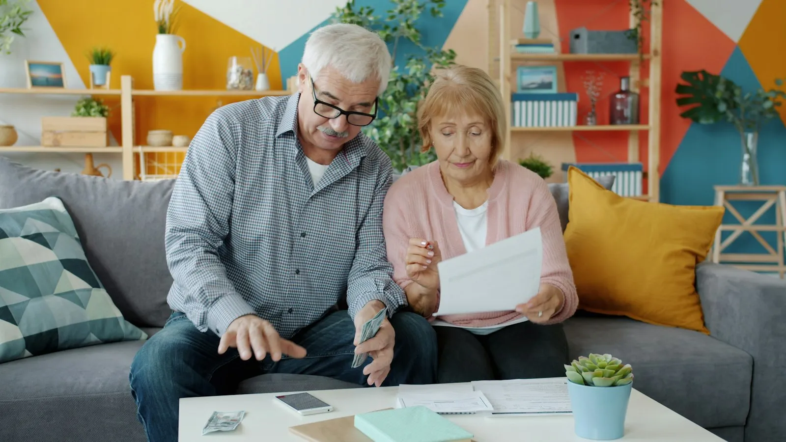 An older couple sitting on a sofa reviewing paperwork together