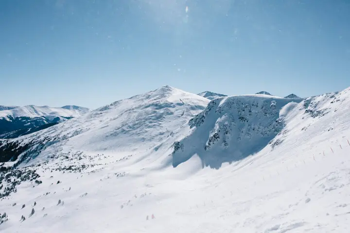A skier crossing a snowy slope below a mountain peak near Breckenridge, Colorado