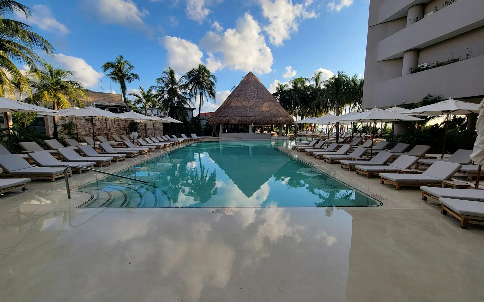 A resort swimming pool lined with lounge chairs and umbrellas