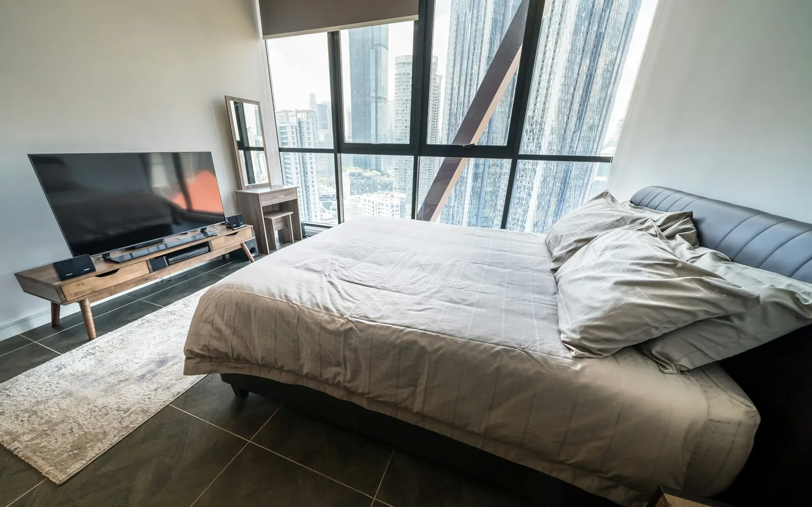 A modern bedroom with a large window and a city view