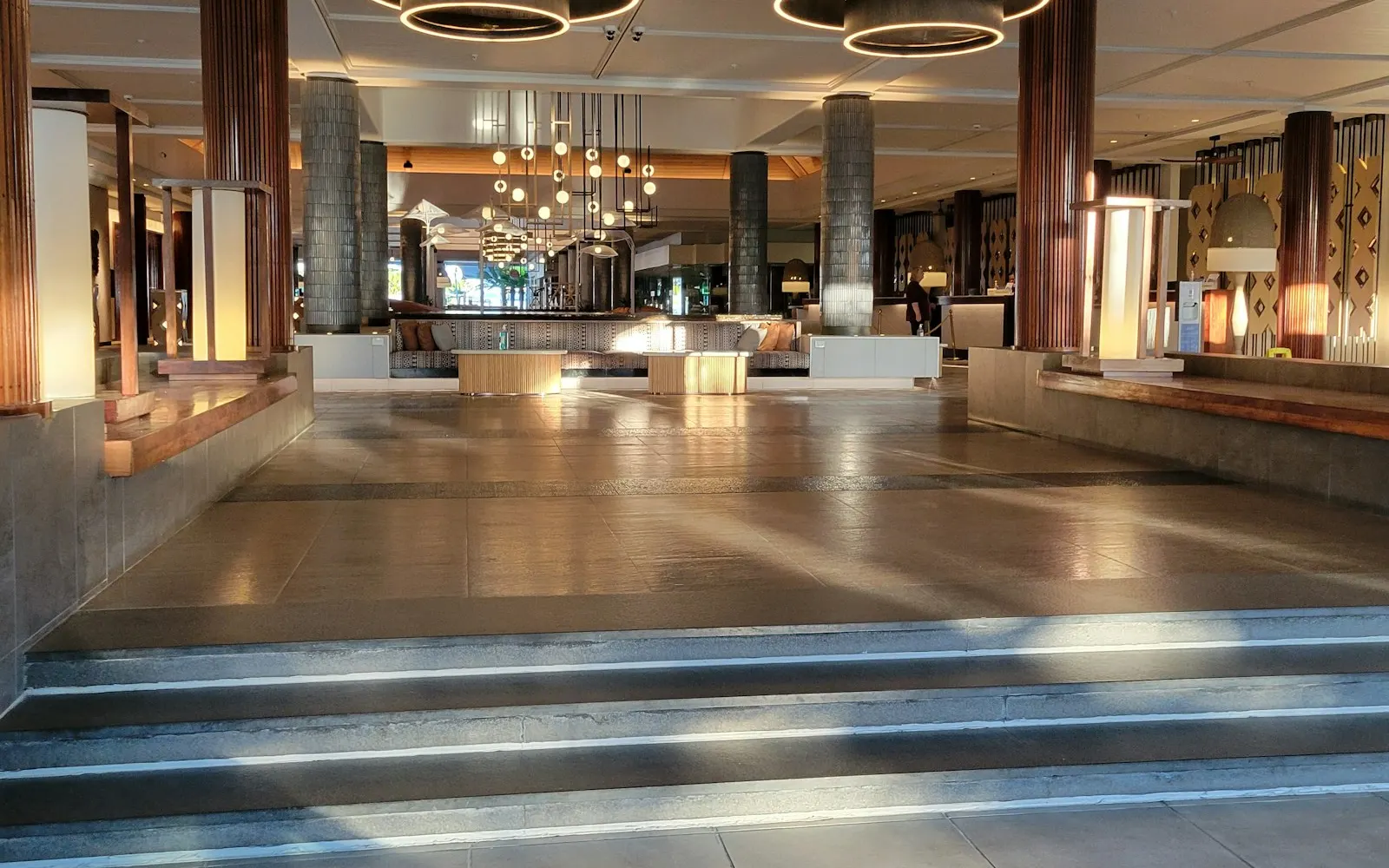 A hotel lobby with a wide staircase and chandeliers